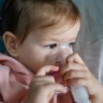 one toddler girl and mother using steam inhaler nebulizer at home