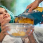 animelike-young-woman-on-the-sofa-holding-bowl-for-more-potato-chips-picture-id1154323014