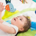 baby-boy-lying-on-back-and-playing-with-toys-picture-id656339092
