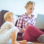 Woman working at home while her baby plays around