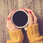 female-hands-in-warm-sweater-holding-cup-of-coffee-picture-id868707272