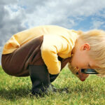Little Boy Exploring Nature Outside with Magnifying Glass