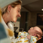 Happy mother spending time with her newborn baby girl at home.