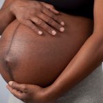 pregnant-woman-caressing-her-belly-over-gray-background-picture-id462682893
