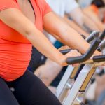 pregnant-woman-working-out-on-a-bike-at-the-gym-picture-id507109350