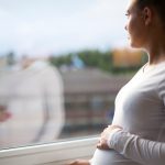 thoughtful-pregnant-woman-looking-out-the-window-picture-id489983342