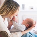 mother-with-her-newborn-baby-son-sitting-on-bed-picture-id639729104