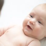 portrait-of-a-cute-smiling-newborn-lying-looking-at-mother-picture-id618200664
