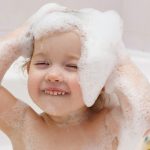 baby-girl-washing-her-hair-with-shampoo-picture-id153175500