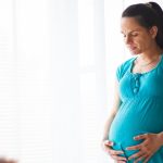 pregnant-woman-standing-with-eyes-closed-picture-id1144943463