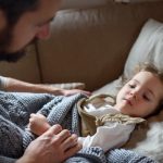 father-checking-on-small-sick-daughter-lying-in-bed-indoors-at-home-picture-id1225471132