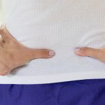 Back pain in woman concept. Female patient hurt from lower backache from bowel and bladder problems, palvic inflammatory disease (PID) or motherhood pregnancy.