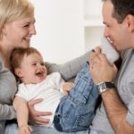 Happy family having fun together laughing, father kissing babies feet.