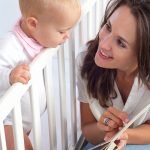 Portrait of a beautiful mother reading book to cute baby