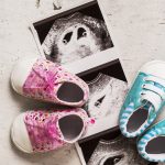 Blue and pink booties next to baby photos with ultrasound in 4th week of pregnancy. Waiting for twins. Son and daughter. Selective focus.