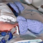 premature-newborn-recovering-in-incubator-his-foot-in-a-blue-sock-an-picture-id1286127052