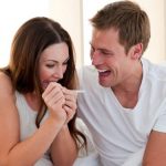 Cheerful couple finding out results of a pregnancy test sitting on bed