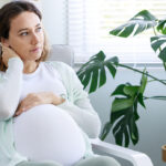 Young woman suffering from nausea and headache during pregnancy