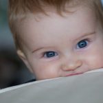 litttle-boy-bites-on-the-edge-of-a-couch-picture-id526767285