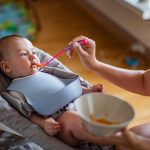 Hungry baby boy is feed by his mother.