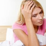 Close-up of ill woman in bed touching her head