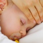 Closeup on mother checking temperature of forehead of baby