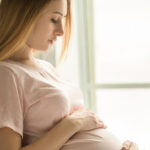 Young preganant woman expecting a baby relaxing on bed indoors