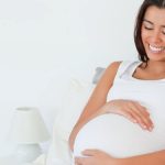 Gorgeous pregnant woman posing while lying on a bed
