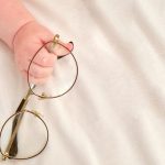 Hand of baby toddler boy holding glasses. Child with eyeglasses frame, close-up