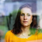 young-woman-looks-thoughtfully-and-sadly-through-the-window-into-the-picture-id1201429767