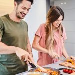 Dieting together. Cheerful young couple preparing healthy meal together