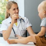 pediatrician-in-office-checking-child-throat-with-wooden-stick-picture-id1264123242