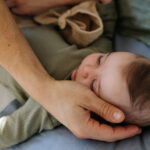 Father putting the baby to sleep, lying next to him in the crib.