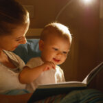 mother reads to baby book in bed