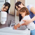 kid-washing-hands-with-mom-in-the-bathroom-picture-id533453244