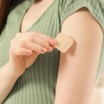 Woman applying contraceptive patch onto her arm indoors, closeup