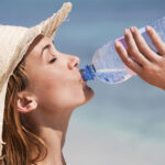 woman drinking water on the beach
