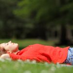 Woman resting lying on the grass in a park or forest