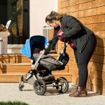 Mother with baby in pram in the backyard on sunny day