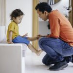 Father helping his son put his shoes on