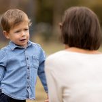 Cute little boy complaining to mother outdoors.