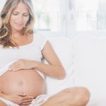 Pregnant woman relaxing on living room.