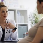The gynecologist consulting a pregnant patient in the clinic