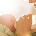 Mother feeding her newborn baby with milk.