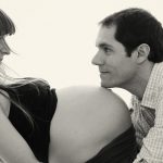Pregnant woman with man touching her belly with his face