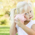 Little Girl Having Fun with Her Piggy Bank Outdoors