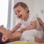 Mom and baby having fun in bedroom