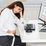 Upset Pregnant Woman Sitting At Computer Desk