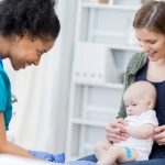 nurse-examines-baby-at-during-check-appointment-picture-id691334462
