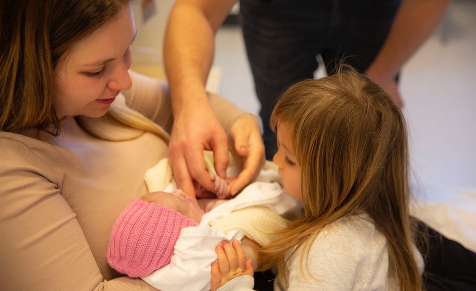 Storesøster ønsket ikke å holde lillesøster selv, men var nysgjerrig på den lille. Foto: Trine-Lise Henriksen